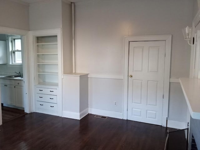 unfurnished bedroom featuring visible vents, baseboards, dark wood-style floors, ensuite bath, and a sink