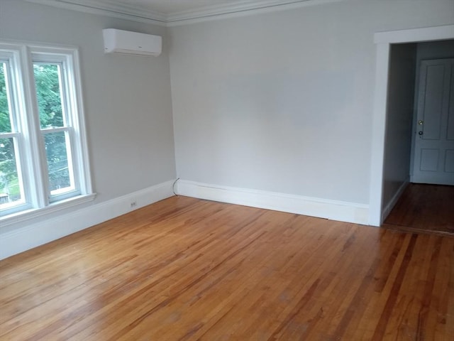 empty room with baseboards, light wood-style floors, an AC wall unit, and ornamental molding