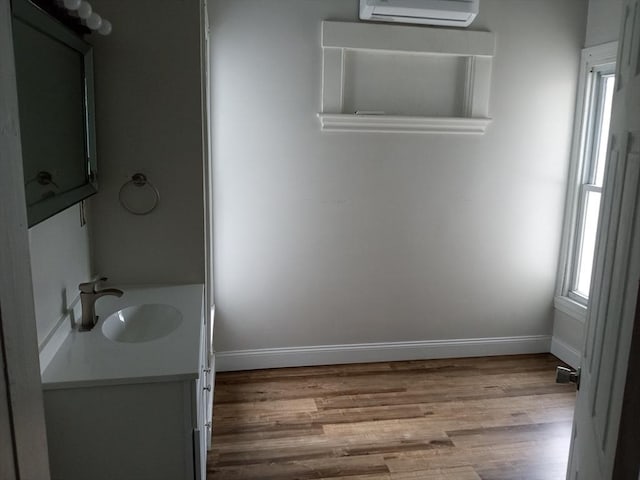 bathroom with an AC wall unit, plenty of natural light, wood finished floors, and baseboards