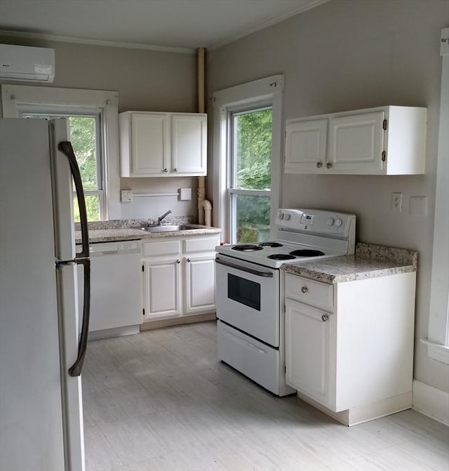 kitchen featuring an AC wall unit, a sink, white cabinetry, white appliances, and light countertops