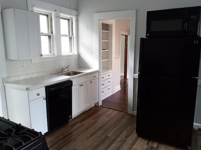 kitchen with dark wood finished floors, a sink, black appliances, white cabinets, and light countertops