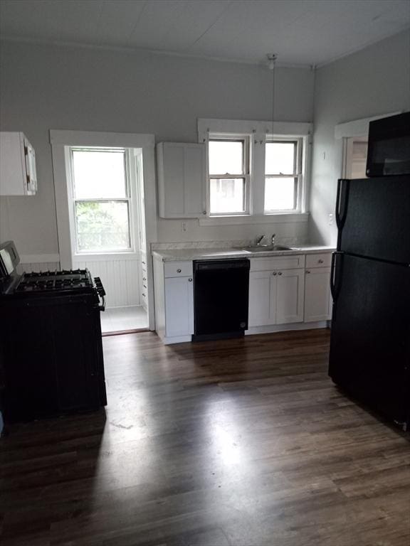 kitchen featuring dark wood finished floors, a sink, black appliances, white cabinets, and light countertops