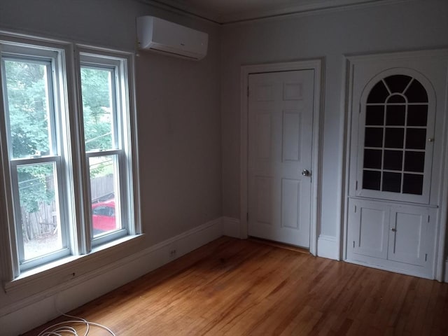 unfurnished room featuring light wood-type flooring, baseboards, a healthy amount of sunlight, and a wall mounted AC