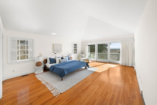 bedroom featuring baseboards, visible vents, hardwood / wood-style flooring, access to exterior, and high vaulted ceiling