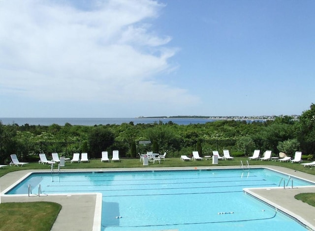 pool with a patio area, a water view, and fence