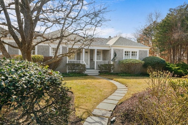 shingle-style home featuring a porch, a shingled roof, and a front lawn