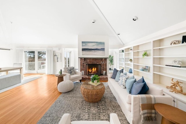 living room featuring high vaulted ceiling, a fireplace, wood finished floors, and built in features