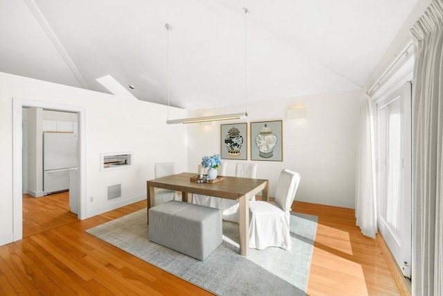 dining area with lofted ceiling, visible vents, and light wood-style flooring