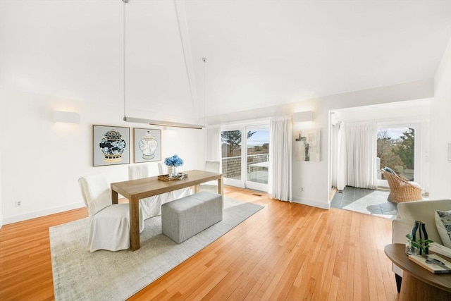 dining space featuring high vaulted ceiling, plenty of natural light, and hardwood / wood-style flooring