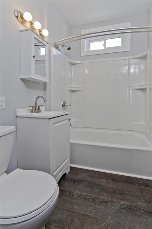 bathroom with toilet, shower / washtub combination, wood finished floors, and vanity