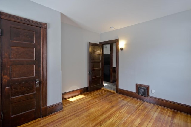 unfurnished room with light wood-type flooring, visible vents, and baseboards