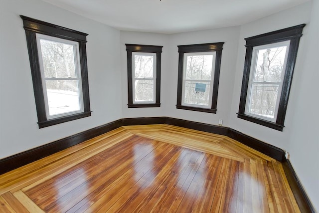 spare room with wood-type flooring and baseboards