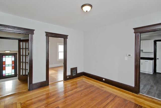 unfurnished room featuring visible vents, baseboards, and hardwood / wood-style floors