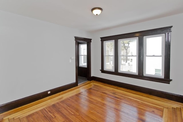 spare room featuring wood-type flooring and baseboards