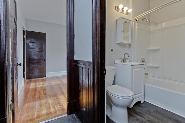 bathroom with baseboards, toilet, vanity, wood finished floors, and shower / bathtub combination