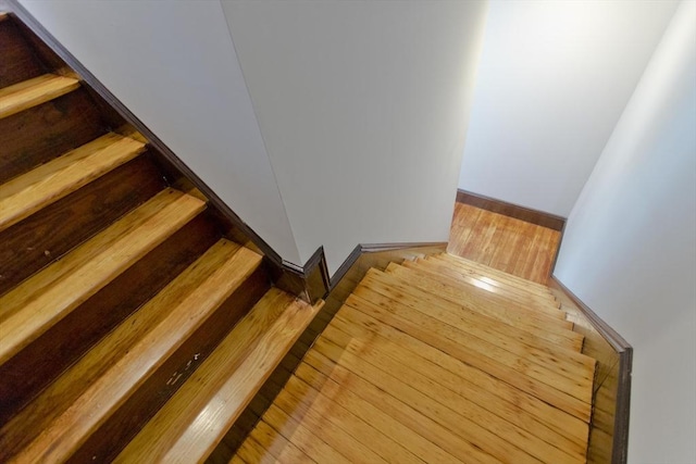 staircase featuring baseboards and wood finished floors