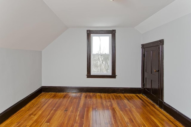 additional living space featuring wood-type flooring, vaulted ceiling, and baseboards