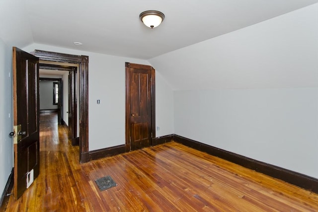 bonus room with lofted ceiling, visible vents, baseboards, and dark wood finished floors