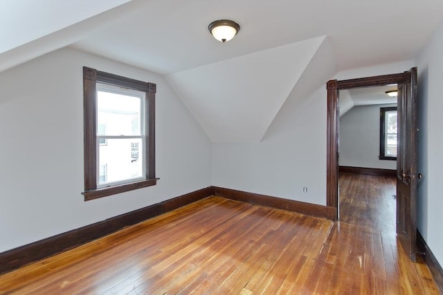 additional living space with vaulted ceiling, hardwood / wood-style flooring, and baseboards