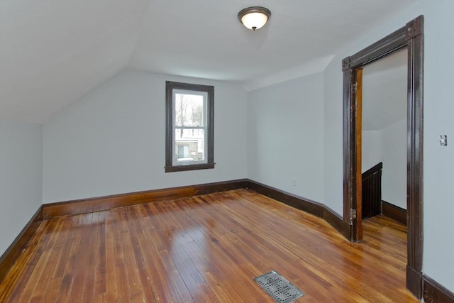 additional living space featuring lofted ceiling, baseboards, visible vents, and hardwood / wood-style floors