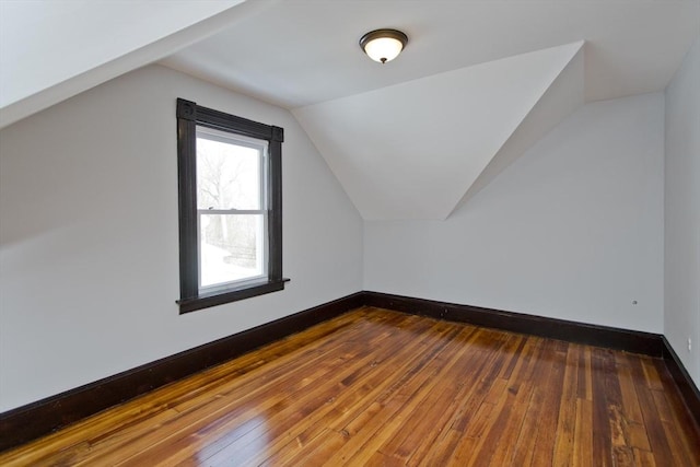 additional living space featuring vaulted ceiling, hardwood / wood-style flooring, and baseboards