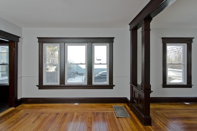 empty room with baseboards, visible vents, and dark wood-type flooring