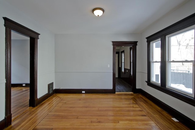 empty room with baseboards, visible vents, and light wood-style floors