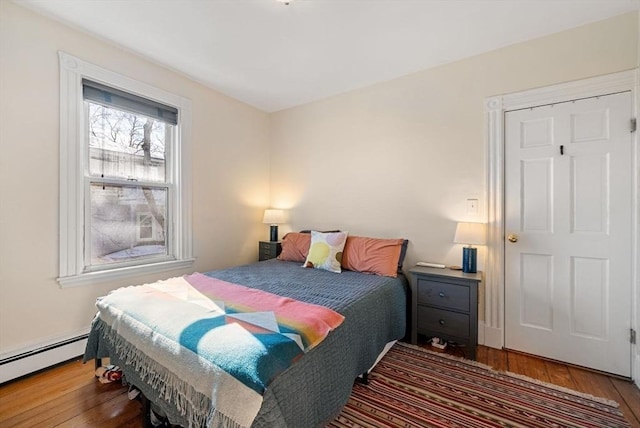 bedroom featuring baseboard heating and hardwood / wood-style floors