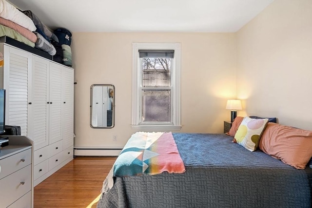 bedroom with baseboard heating and wood finished floors