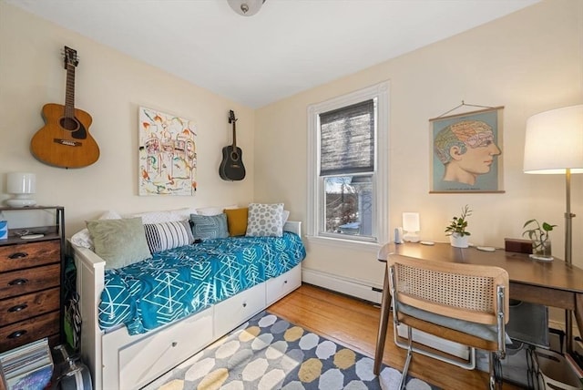 bedroom with baseboard heating, baseboards, and wood finished floors