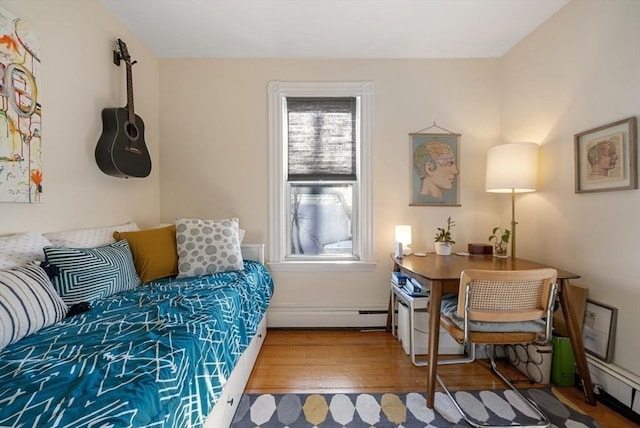 bedroom with wood finished floors and a baseboard radiator