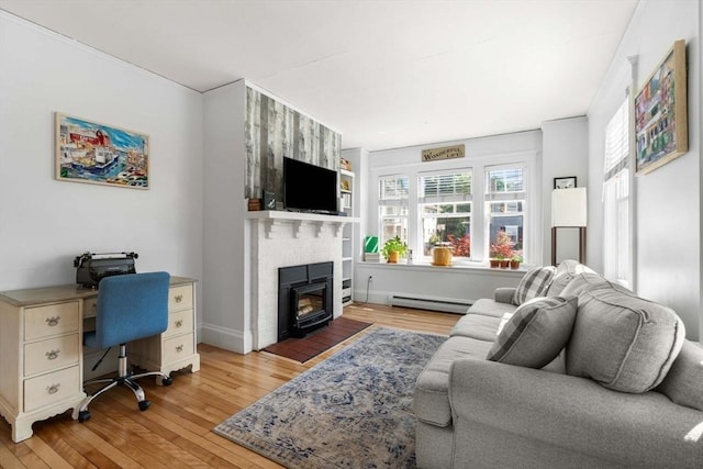 living area with a baseboard heating unit, a brick fireplace, and light wood finished floors