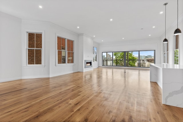 unfurnished living room with ornamental molding, light wood-type flooring, and a fireplace