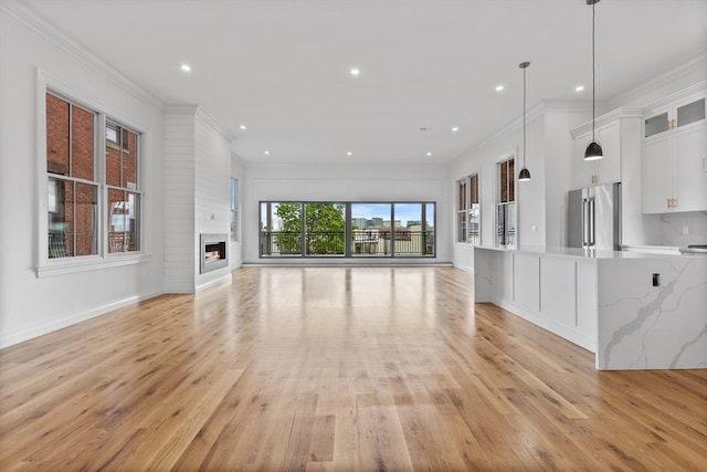 unfurnished living room with crown molding, light wood-type flooring, and a fireplace