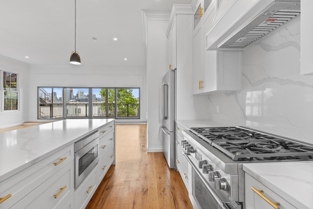 kitchen with light wood-type flooring, premium range hood, decorative light fixtures, high end appliances, and tasteful backsplash