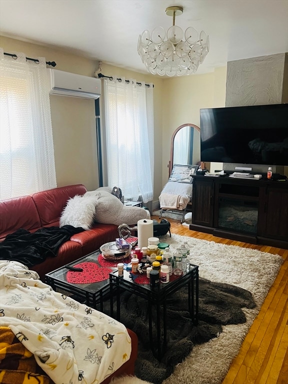 living room with a notable chandelier, a wall mounted air conditioner, and hardwood / wood-style floors