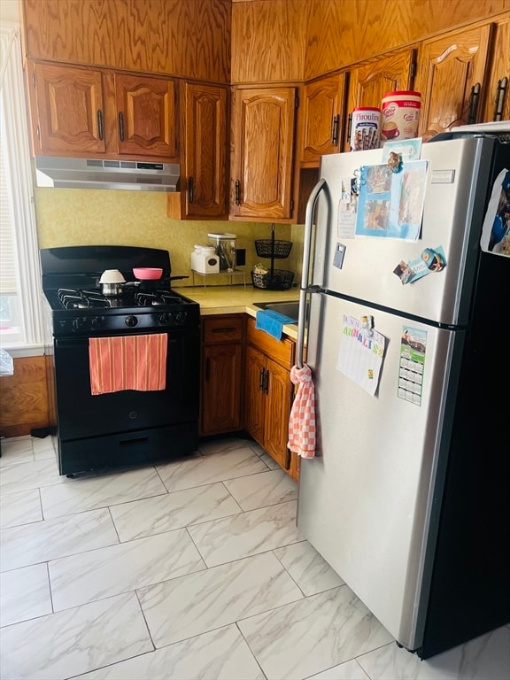 kitchen with black range with gas cooktop and stainless steel fridge