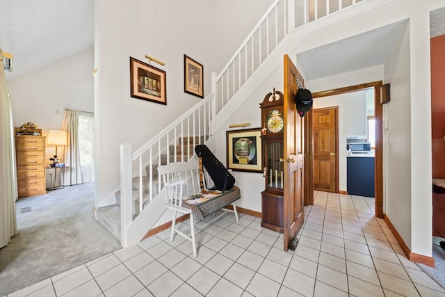 stairway with tile patterned floors and a towering ceiling