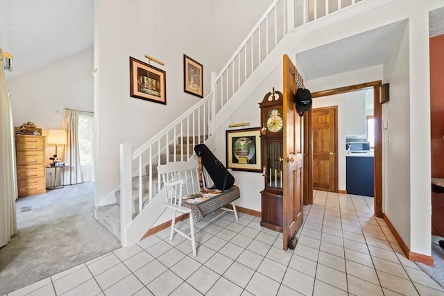 stairs featuring tile patterned flooring, baseboards, high vaulted ceiling, and carpet