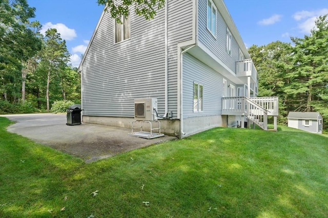 view of side of home featuring a patio, stairway, a yard, an outdoor structure, and ac unit