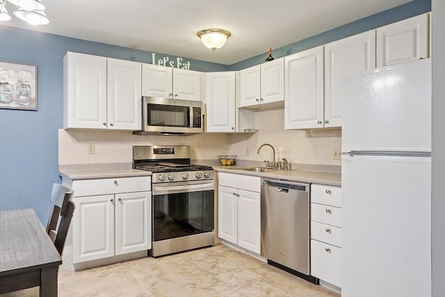 kitchen featuring a sink, white cabinets, light countertops, appliances with stainless steel finishes, and tasteful backsplash
