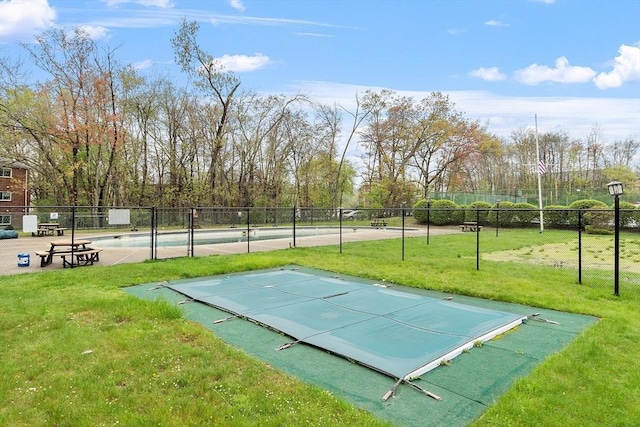 view of property's community featuring a lawn, a swimming pool, and fence