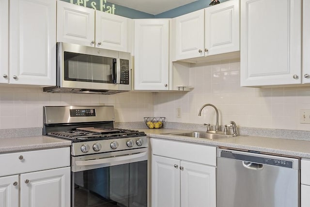 kitchen with a sink, stainless steel appliances, white cabinetry, and light countertops