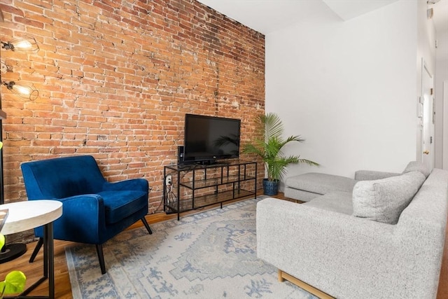 living area featuring wood finished floors and brick wall