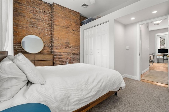 carpeted bedroom featuring a closet, visible vents, brick wall, baseboards, and recessed lighting
