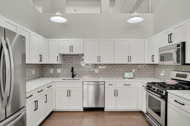 165 Chestnut Hill Ave Unit 3, Boston, MA 02135 - kitchen featuring appliances with stainless steel finishes, light countertops, white cabinetry, wood finished floors, and a high ceiling
