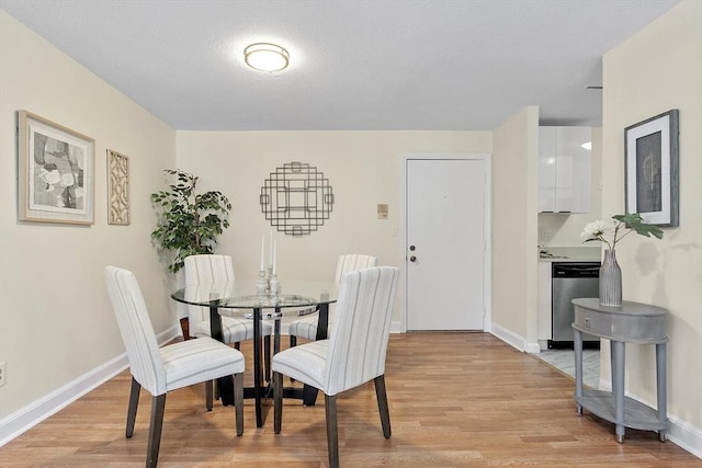 dining space with a textured ceiling and light hardwood / wood-style flooring