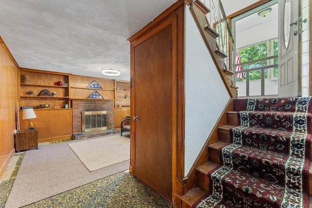 30 Stone St, Bellingham, MA 02019 - stairs with built in shelves, a brick fireplace, wooden walls, and a textured ceiling