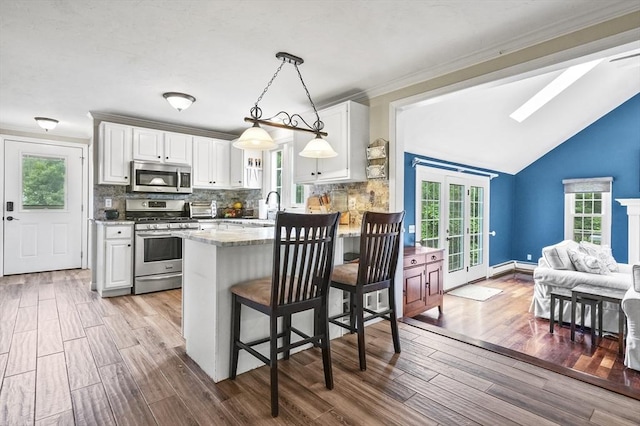 323 School St, Pembroke, MA 02359 - kitchen featuring stainless steel appliances, white cabinetry, a kitchen breakfast bar, backsplash, and a peninsula