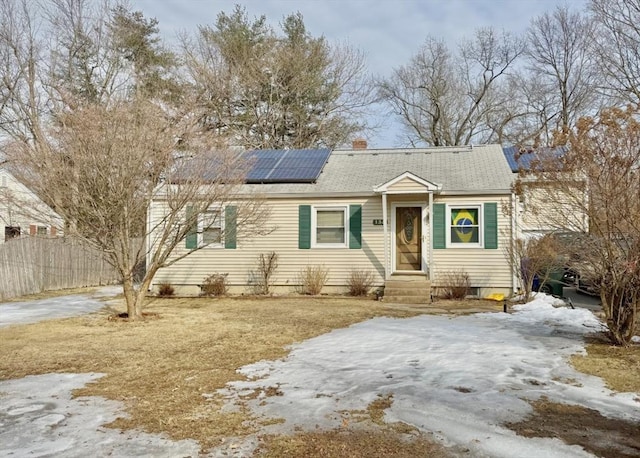 view of front of property featuring roof with shingles, a chimney, fence, and roof mounted solar panels